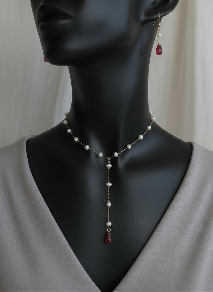 Pearl necklace with red accents on a mannequin bust.